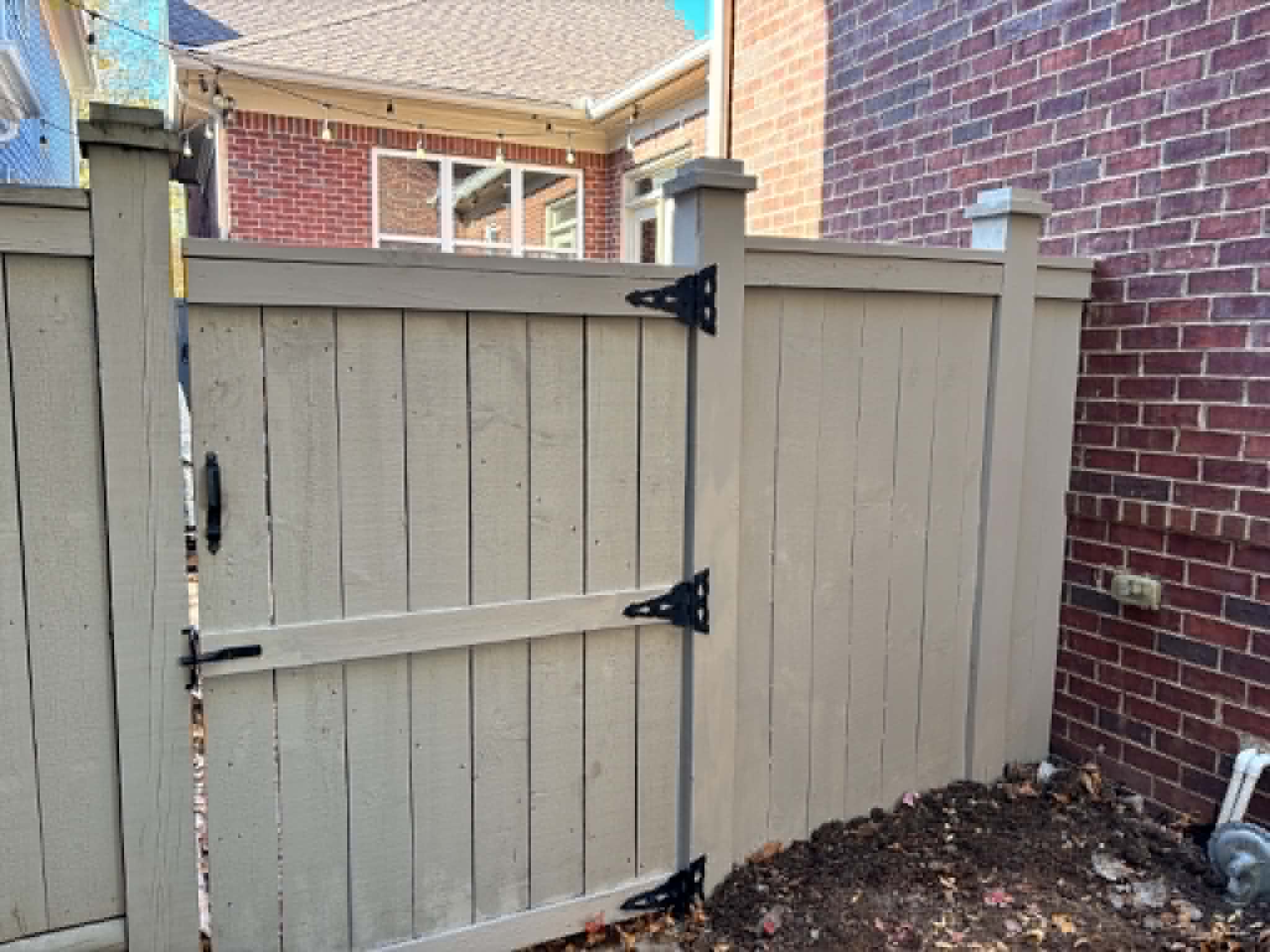 Custom painted fence with gate against brick wall in Middle Tennessee